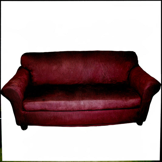 Gray elastic furniture cover on a three-seater sofa, showing snug fit and soft fabric for protection and style.
